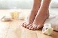 Woman with beautiful feet, towel and flowers on wooden floor. Spa treatment Royalty Free Stock Photo