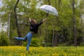 Woman with a beautiful figure reaches for a flying transparent umbrella in the park