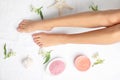 Woman with beautiful legs, cosmetic and flowers on white towel, top view. Royalty Free Stock Photo