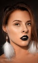 Woman with beautiful makeup and black lipstick on her lips, in the Gothic style. She has white feather earrings. Makeup and Royalty Free Stock Photo
