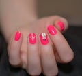 Woman with beautiful manicured pink fingernails gracefully crossing her hands to display them to the viewer on a blue background Royalty Free Stock Photo