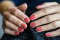 Woman with beautiful manicured red fingernails gracefully crossing her hands to display them to the viewer on a gray Royalty Free Stock Photo