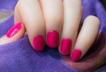 Woman with beautiful nail blue fingernails gracefully crossing her hands to display them to the viewer on a pink background in a Royalty Free Stock Photo