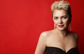 Woman Beauty with Blond Short Hairstyle over Red Background. Smiling Fashion Blonde Model with Pixie Hair Cut in evening Dress Royalty Free Stock Photo