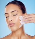 Woman, beauty and face massage with gua sha, facial product or aesthetic skincare in studio. Young model, crystal stone