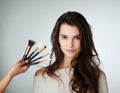 Woman, beauty and makeup brush for face in studio with a natural glow. Portrait of female person on a grey background Royalty Free Stock Photo