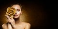 Woman Beauty Perfect glowing Skin Makeup. Fashion Model holding Golden Rose Flower over Face and covering Closed Eye. Artistic Royalty Free Stock Photo