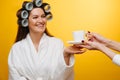 Woman in a beauty salon sits with hair in rollers, being served tea by a staff Royalty Free Stock Photo