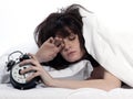 Woman in bed awakening tired holding alarm clock