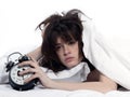 Woman in bed awakening tired holding alarm clock