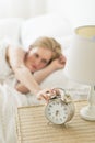 Woman In Bed Pressing Button On Alarm Clock Royalty Free Stock Photo