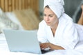 Woman on a bed after showering using laptop