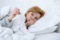woman in bed with thermometer feverish weak suffering winter cold flu virus Royalty Free Stock Photo