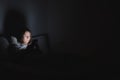 Woman in bed uses phone late at night.