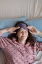 woman in bed wakes up, insomnia and sleep disorder. person in sleep mask holds his head and face Royalty Free Stock Photo