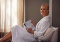 Woman, bedroom and smile on bathrobe with magazine for entertainment, news and relax for leisure. Female person, home