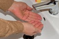 The woman begins to wash her hands in the sink by placing them under the tap. Royalty Free Stock Photo