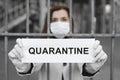 A woman behind bars in isolation holds a placard reading quarantine . Message for the prevention of coronavirus covind