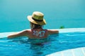Woman from behind in hat and infinity pool looking away. New travel season concept. 2017 written on back by suncream