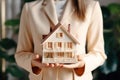 woman in beige business suit holds model of an apartment building in her palms,hands in close-up Royalty Free Stock Photo