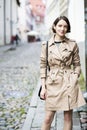 Woman at beige coat with handbag smile stealthily Royalty Free Stock Photo
