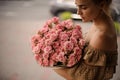 Woman in beige dress gently holds bouquet with pink flowers Royalty Free Stock Photo