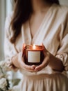 Woman in beige dress holding burning candle, design and branding ready candle jar mockup with female hands, no face Royalty Free Stock Photo