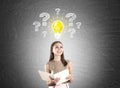 Woman in beige, light bulb, questions, blackboard Royalty Free Stock Photo