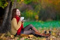 Woman in beige sweater and red scarf drink tea