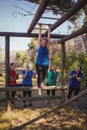 Woman being cheered bye her teammates to climb monkey bars during obstacle course training Royalty Free Stock Photo
