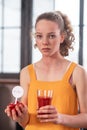 Calm and upset young woman staying with glass of tomato juice