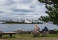 A Woman on a bench sitting alone. Bridge and Lake background.