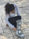 Woman bending down in the street adjusting the orthopedic walking boot, ideal for walking people with leg injuries such as tibia