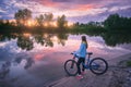 Woman with bicycle on the coast of the river at sunset in summer Royalty Free Stock Photo