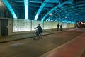 Woman on bicycle moving under bridge - editorial