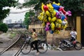 Woman on a bicycle selling Despicable Me helium balloons in Hanoi