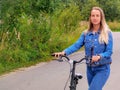 Woman with bicycle walking on rural road Royalty Free Stock Photo