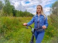 Woman with bicycle walking on rural road Royalty Free Stock Photo