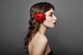 Woman with a big red flower in her hair. Brown-haired girl with a red flower posing on a gray background. Big beautiful eyes Royalty Free Stock Photo