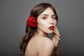 Woman with a big red flower in her hair. Brown-haired girl with a red flower posing on a gray background. Big beautiful eyes Royalty Free Stock Photo