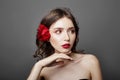 Woman with a big red flower in her hair. Brown-haired girl with a red flower posing on a gray background. Big beautiful eyes Royalty Free Stock Photo