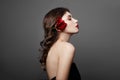 Woman with a big red flower in her hair. Brown-haired girl with a red flower posing on a gray background. Big beautiful eyes Royalty Free Stock Photo