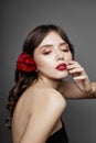 Woman with a big red flower in her hair. Brown-haired girl with a red flower posing on a gray background. Big beautiful eyes Royalty Free Stock Photo