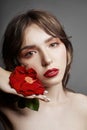 Woman with a big red flower in her hair. Brown-haired girl with a red flower posing on a gray background. Big beautiful eyes Royalty Free Stock Photo