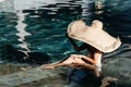 Woman in big straw hat relaxing at pool. Royalty Free Stock Photo