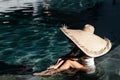 Woman in big straw hat relaxing at pool. Royalty Free Stock Photo