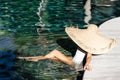 Woman in big straw hat relaxing at pool. Royalty Free Stock Photo