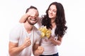 Woman with big toothy smile holding boyfriends eyes giving him a present for Valentine's day.