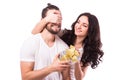 Woman with big toothy smile holding boyfriends eyes giving him a present for Valentine's day.