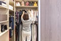 Woman in big walkin closet choosing clothes. modern wardrobe and dressing room with copy space